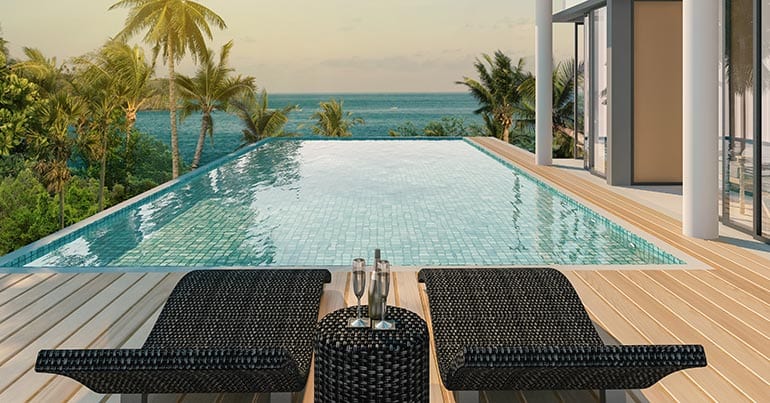 Two lounge chairs next to an infinity pool overlooking the ocean
